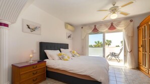 A bedroom with a bed, a nightstand, a ceiling fan, and a view of the outside. - Septimo Cielo by Interhome (Calpe/Calp)