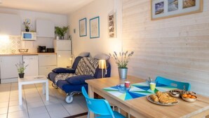 Een compacte leefruimte met een kitchenette, een eethoek met een tafel en stoelen, en een bank.
