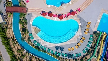 An aerial view of a resort with a large central pool, multiple smaller pools, and a variety of sun loungers and umbrellas.