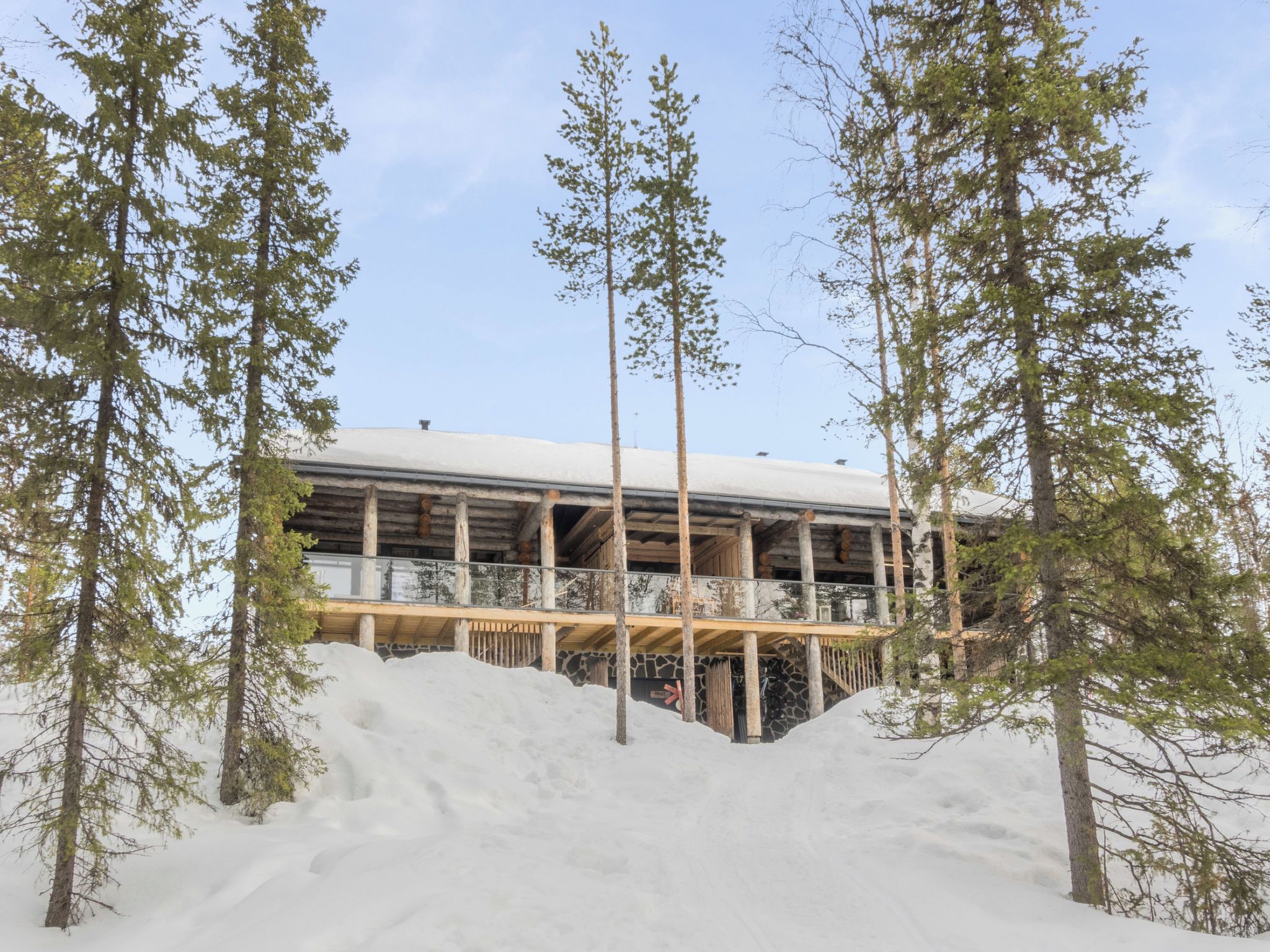 Un bâtiment en bois doté d’un balcon, entouré de neige et d’arbres.