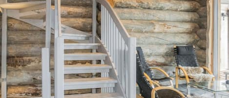 A spiral staircase with white railings leading to a log cabin interior.