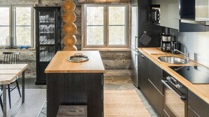 Una cocina moderna con una isla central, vigas de madera y ventanas amplias.