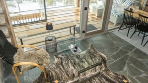 Un interior moderno con techo de cristal, piso de piedra, alfombra de piel y vistas al exterior.