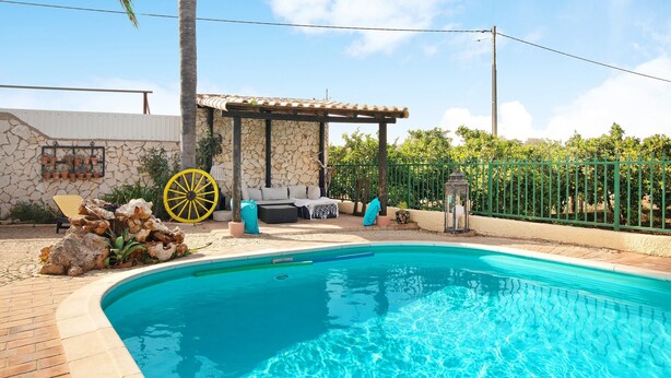 Une piscine bordée d’un muret en pierre, un espace détente abrité et un jardin clôturé.