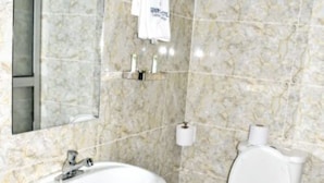 Casa de banho com lavatório de mármore, sanita e toalha pendurada num suporte.
