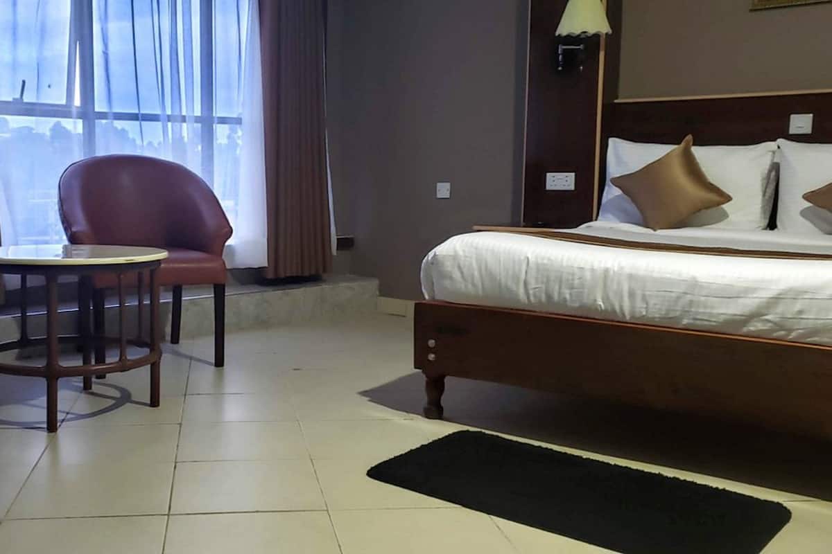 A hotel room with a bed, two armchairs, a small round table, and a view through the window.