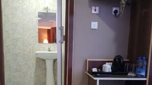 Uma casa de banho pequena com chuveiro, lavatório e um armário com artigos de higiene pessoal.