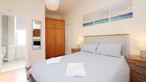 Ein Schlafzimmer mit Bett, Nachttisch, Holzschrank, Spiegel und einem Bild an der Wand.