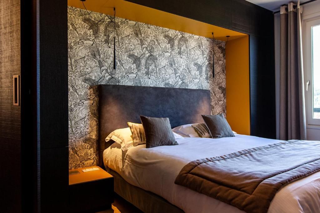 A modern hotel room with a large bed, a headboard with a floral pattern, and a nightstand.
