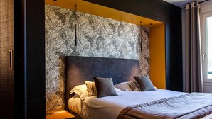 A modern hotel room with a large bed, a headboard with a floral pattern, and a nightstand. - Logis Hotel de la Tour (Dunieres)
