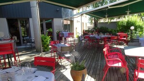 Un patio al aire libre con mesas y sillas, algunas con sombrillas.