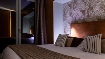 Hotelkamer met een groot bed, een gestreept hoofdeinde en uitzicht door een schuifdeur.