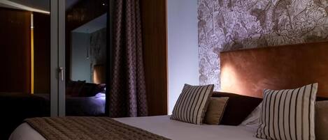 Ett hotellrum med en stor säng, en sänggavel med mönster och utsikt genom en skjutdörr.