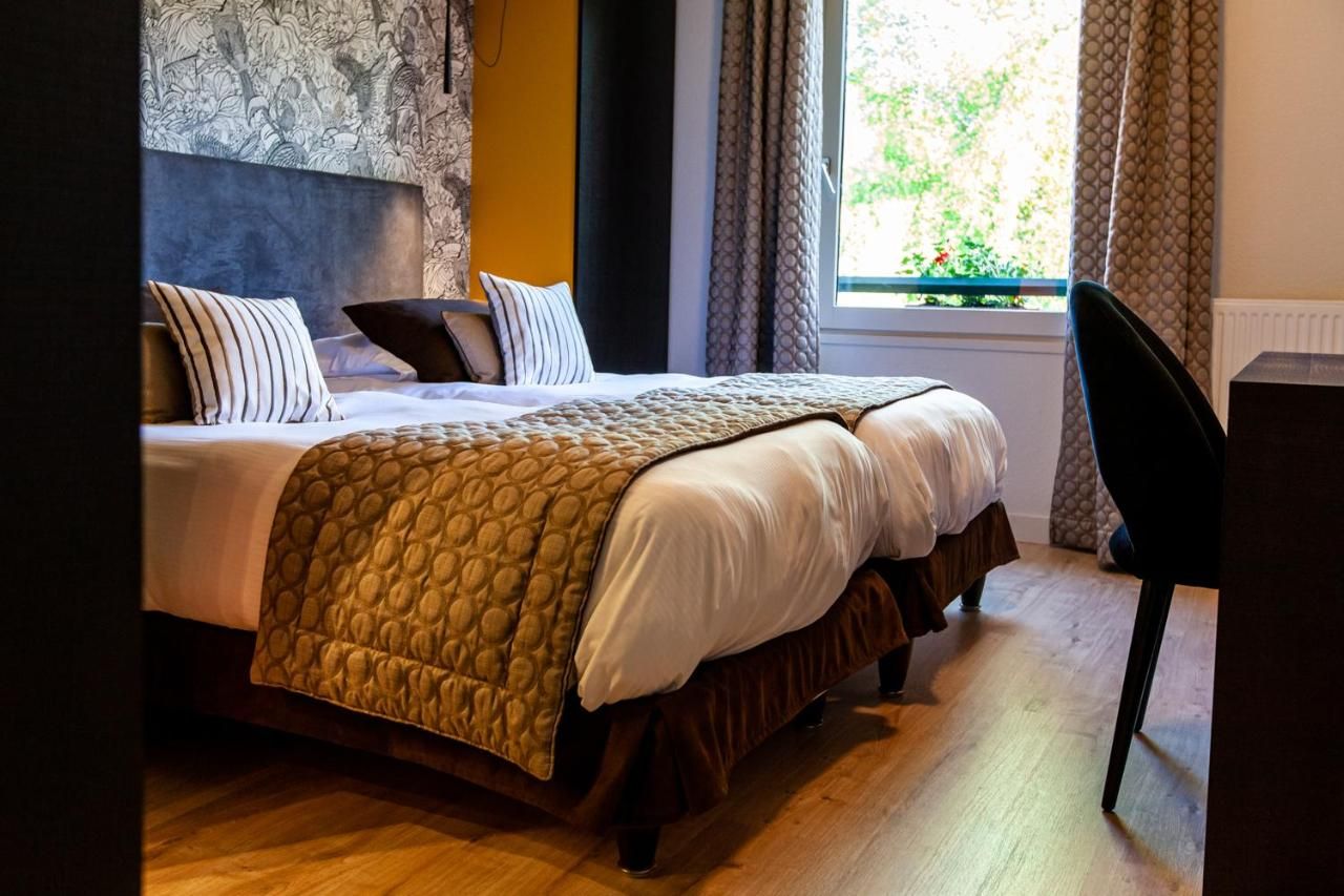 A neatly made bed with a patterned blanket, a headboard with a floral design, and a window with curtains.