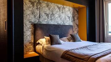 A modern hotel room with a large bed, a headboard with a floral pattern, and a nightstand.