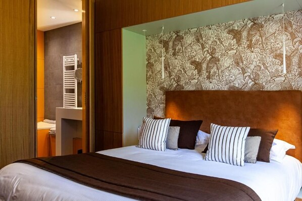 Ein Hotelzimmer mit einem großen Bett, einem hölzernen Kopfteil und einer Wand mit floralem Wandteppich.