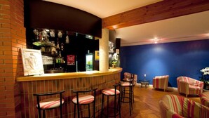 A bar area with stools, a counter, and a seating area with striped chairs. - Logis Hotel de la Tour (Dunieres)