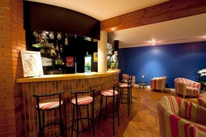 Eine Bar mit Barhocker, Theke und einer Sitzecke mit gestreiften Stühlen.