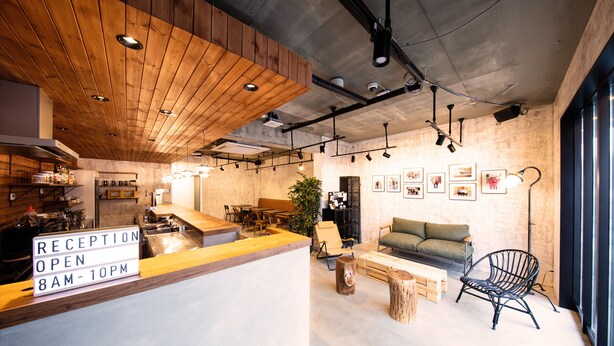 A reception area with a wooden counter, a reception desk, and a sign indicating the hours of operation. - Ten to Ten Hostel (Sapporo)