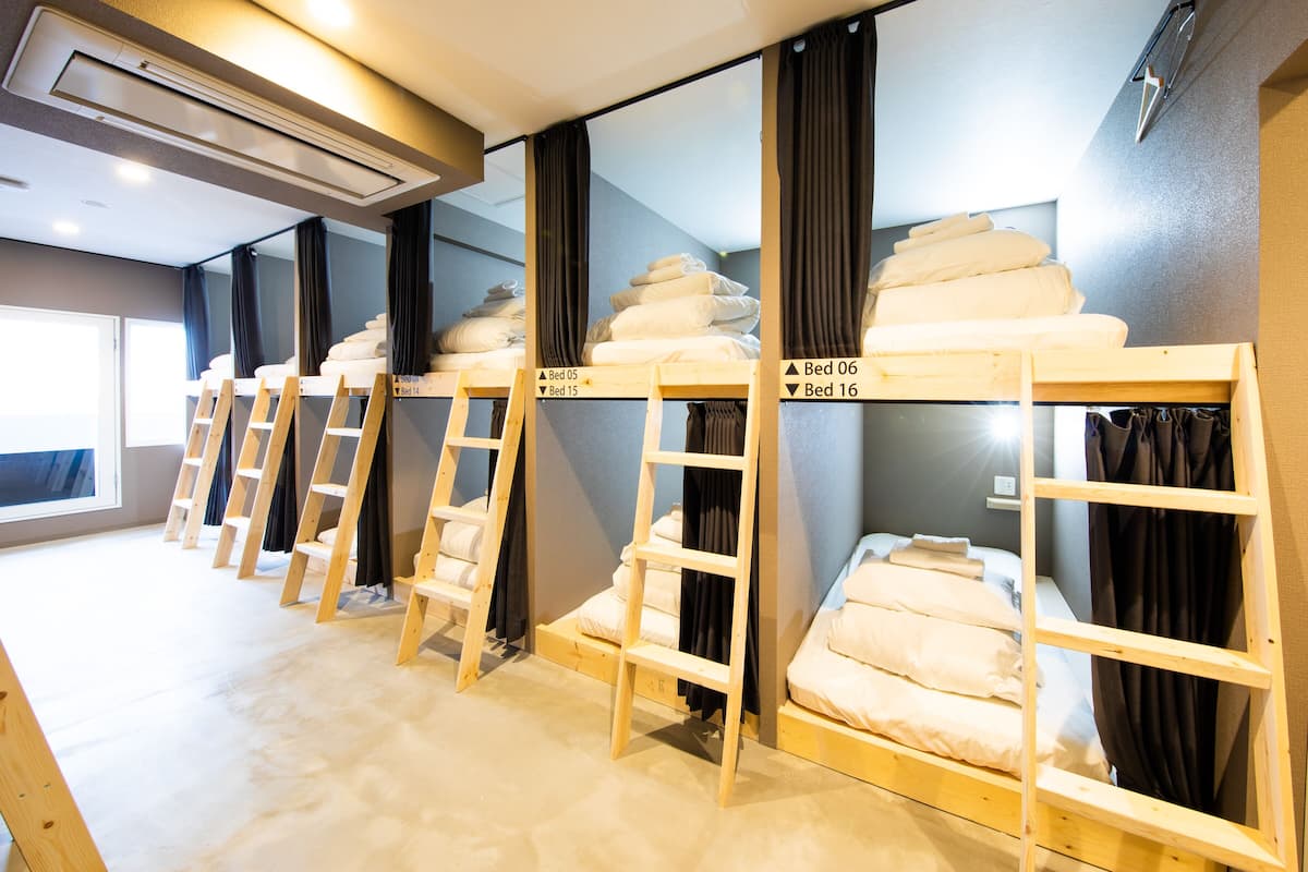 Bunk beds with labels indicating their numbers, wooden ladders, and a window with curtains.
