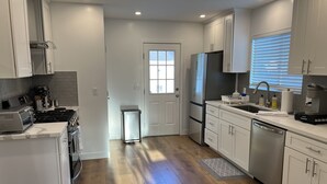Una cocina moderna con armarios blancos, electrodomésticos de acero inoxidable y suelo de madera.