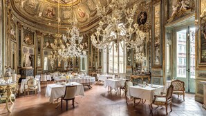A grand dining room with ornate chandeliers, classical paintings, and a luxurious ambiance. - Palazzo Doria Napoli (Naples)