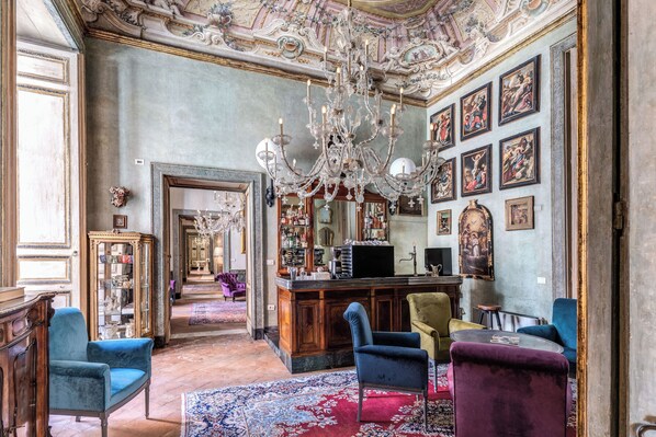 An opulent room with a bar, ornate ceiling, and classical artwork.