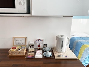 Una estación de té ordenada con una caja de té, tetera, tazas y un hervidor sobre una bandeja de madera.