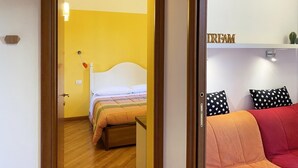 A room with a bed, a bedside table, a red sofa, and a shelf with the word 'DREAM' on it.
