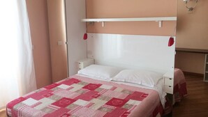 Une chambre à coucher avec un lit, une table de chevet, une lampe rouge et un luminaire fixé au mur.