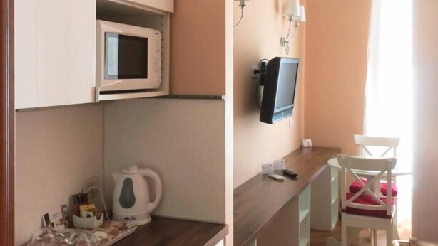 Une petite cuisine équipée d’un micro-ondes, d’une bouilloire et d’un coin repas avec une chaise et une table.