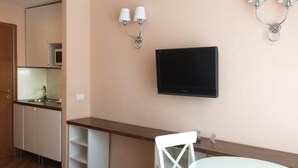 Une cuisine compacte équipée d’un micro-ondes, d’un évier et de placards. On y trouve également un coin repas avec une chaise blanche et une petite table ronde.