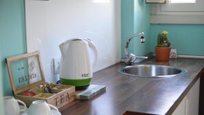 A kitchen with a wooden countertop, a kettle, a sink, a potted plant, and a framed picture. - Luna Rossa Guest House   Green Double room with garden view (ROMA)