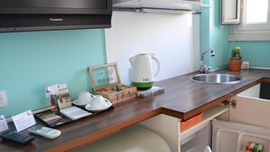 A kitchen with a wooden countertop, a white kettle, a sink, and a refrigerator. - Luna Rossa Guest House   Green Double room with garden view (ROMA)