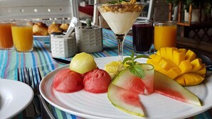 A breakfast setting with a plate of fruit, a glass of orange juice, and a dessert in a martini glass. - Mnarani Beach Club (Malindi)
