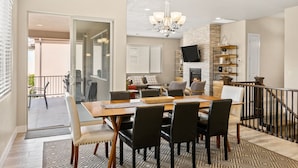 A dining area with a large wooden table and chairs, a chandelier, and a fireplace. - Snow Canyon Paradise #46 by RedAwning (Ivins)