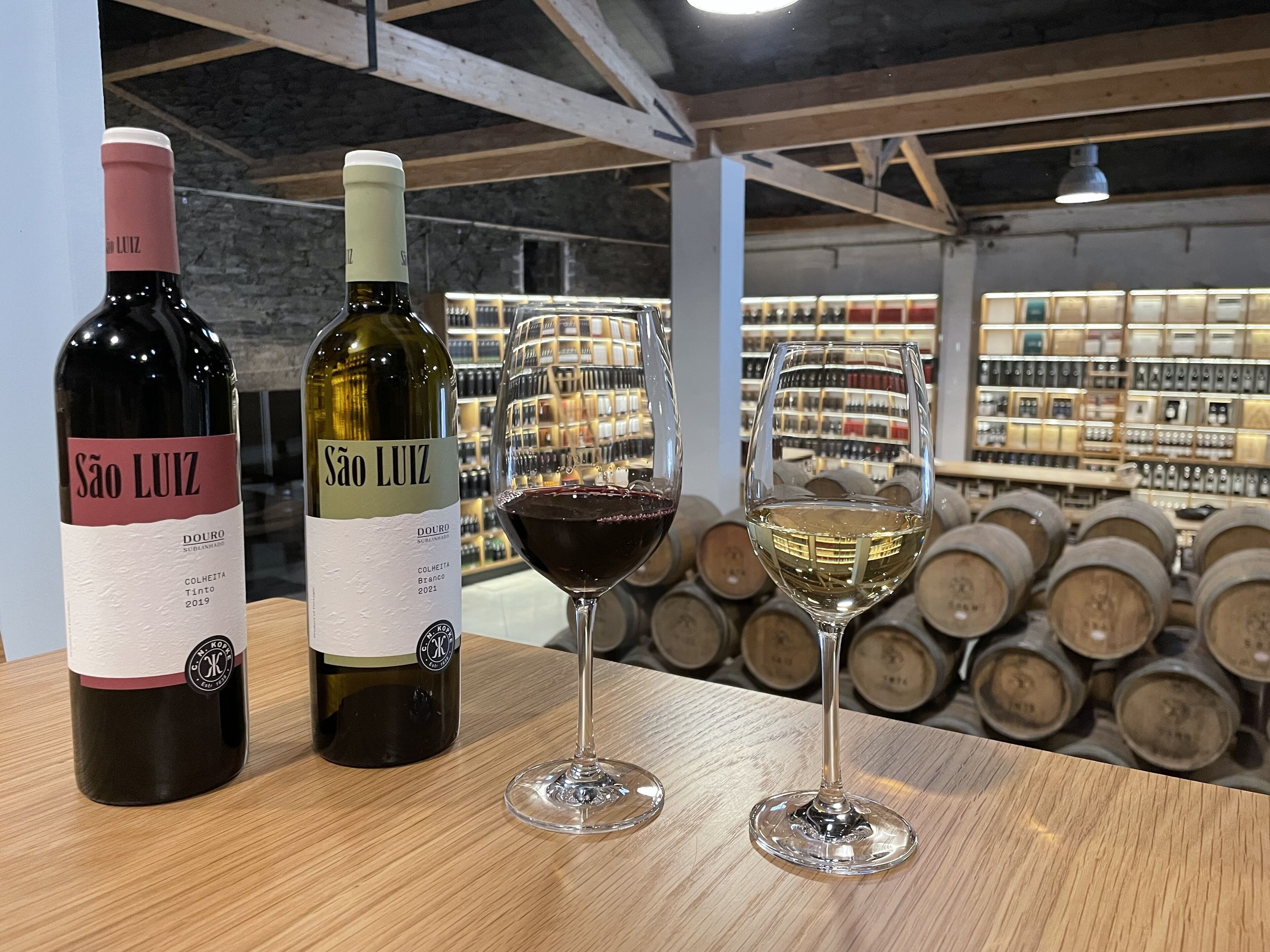 Dos botellas de vino y dos copas de vino sobre una mesa de madera en una bodega.