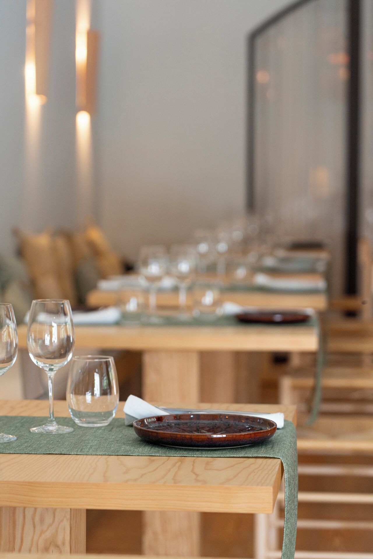 A row of tables with empty wine glasses and plates, suggesting a dining area in a restaurant.