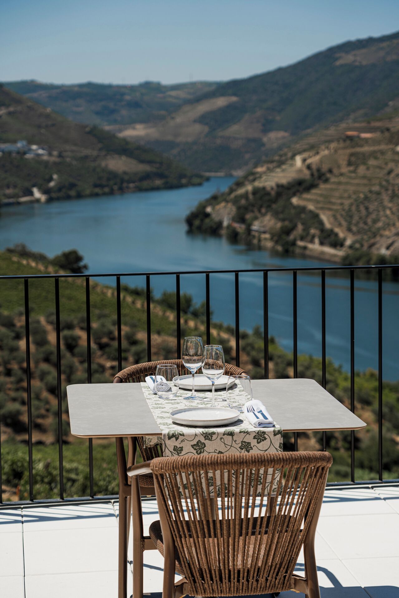 A table set for two with a view of a lake and hills in the background.