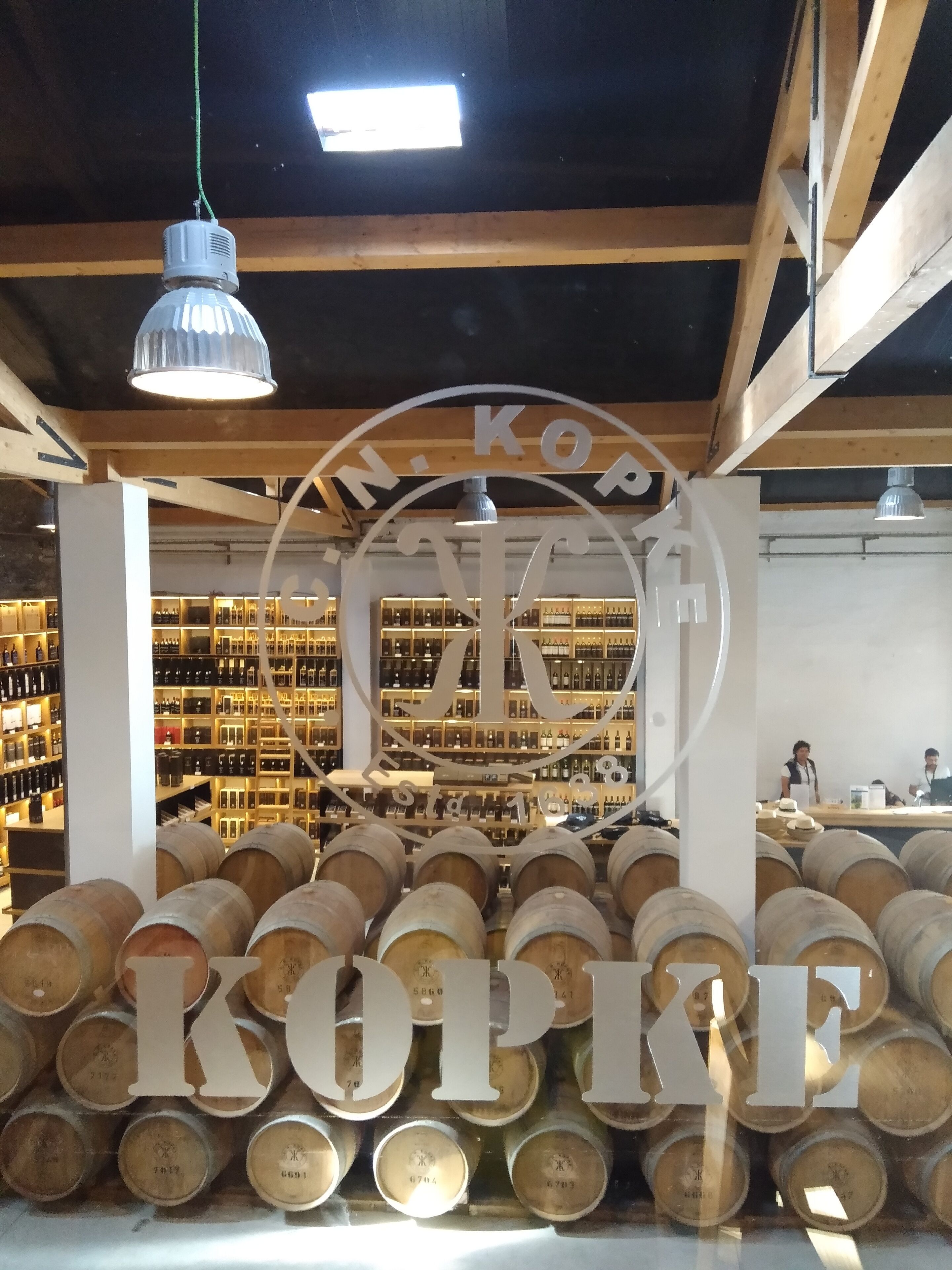 A wine cellar with wooden barrels and shelves of wine bottles.