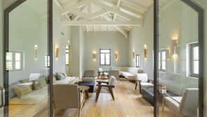 Amplia habitación con techo alto, suelo de madera y una variedad de opciones de asientos, incluyendo sofás y sillones.