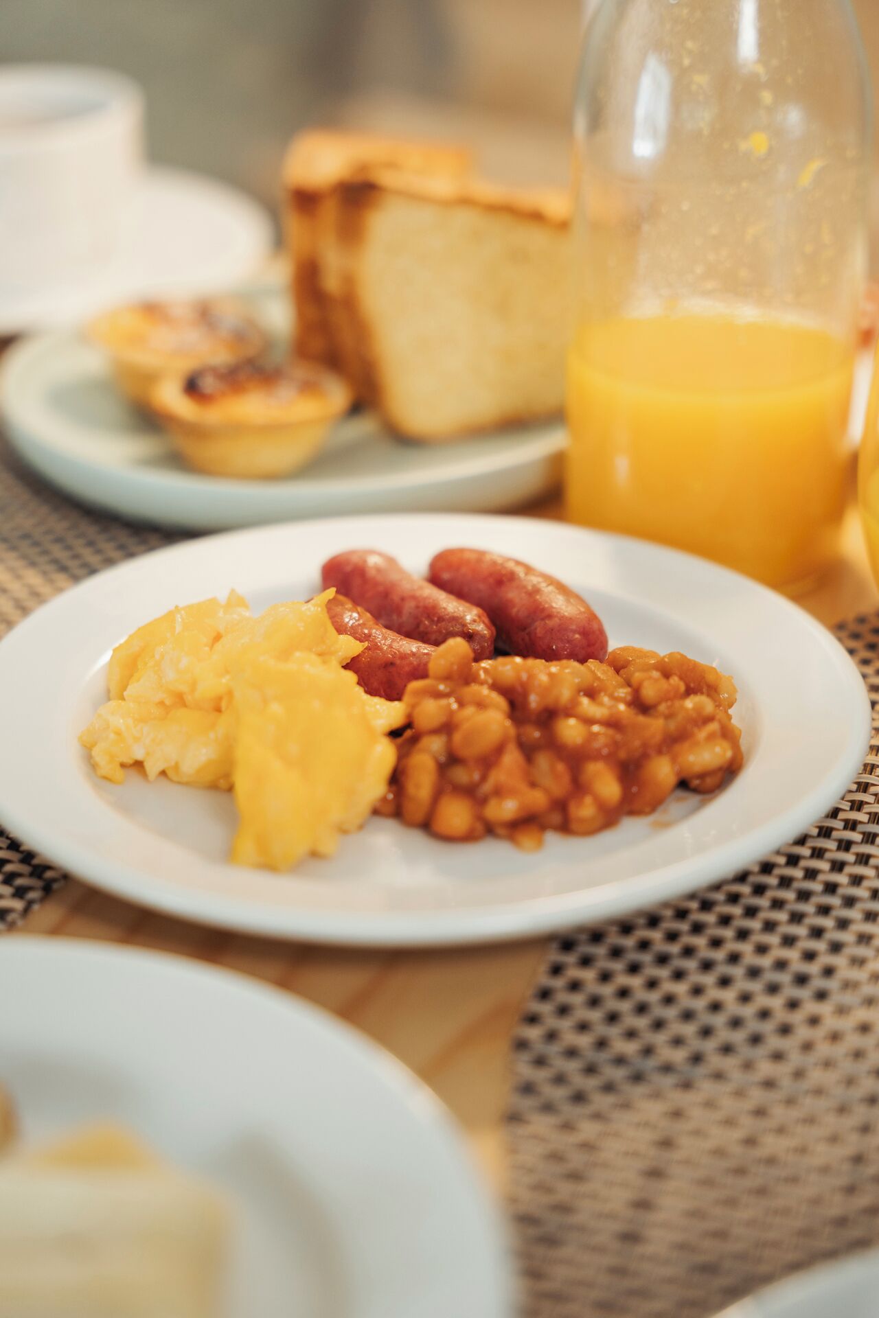 A breakfast plate with scrambled eggs, sausages, and baked beans.