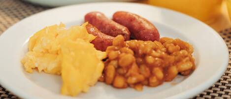 A breakfast plate with scrambled eggs, sausages, and baked beans.