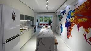 Une cuisine moderne dotée d’un îlot en marbre, de meubles blancs et d’une carte du monde colorée accrochée au mur.