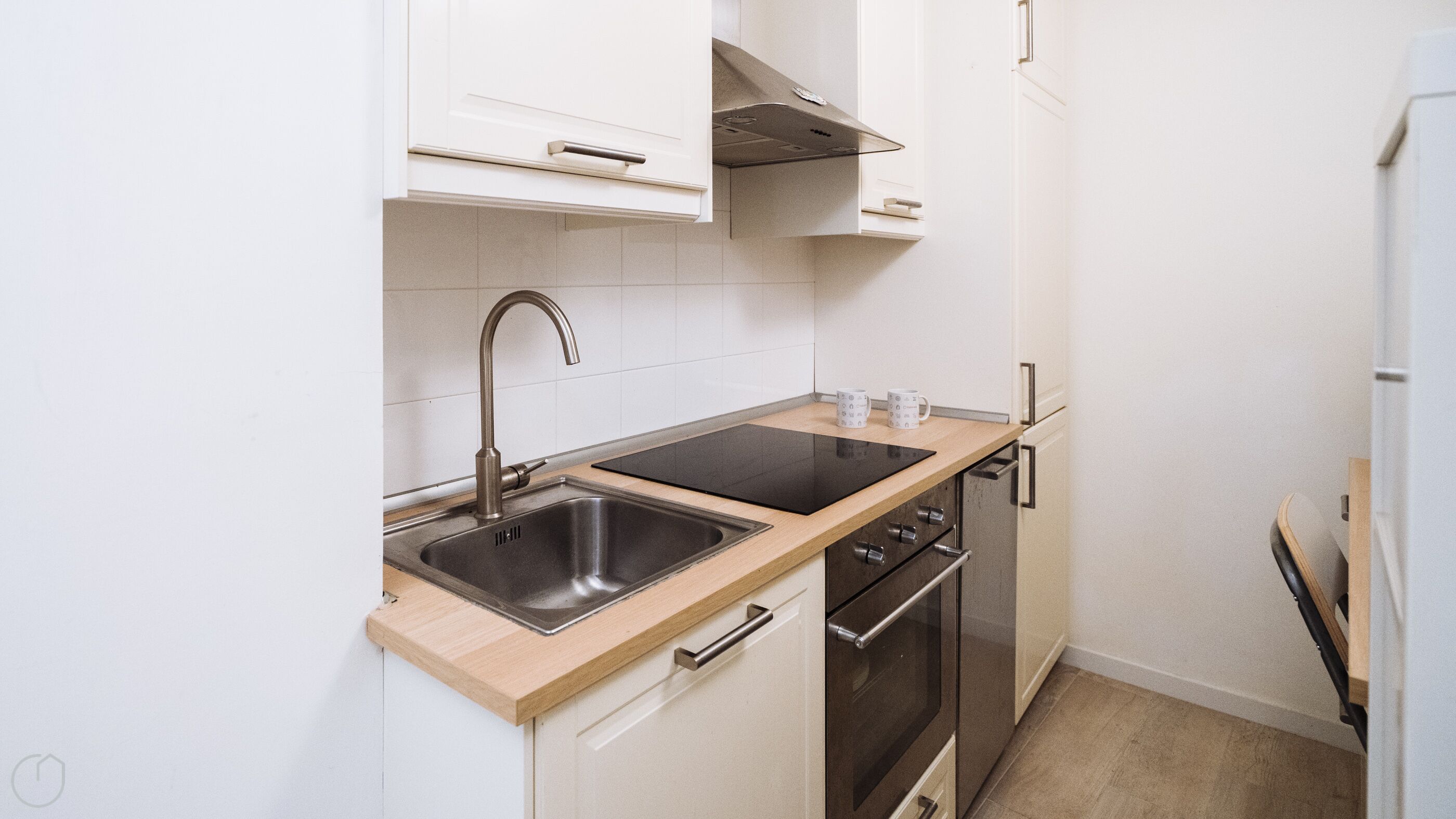 A compact kitchen with a double sink, a stove, and a microwave.
