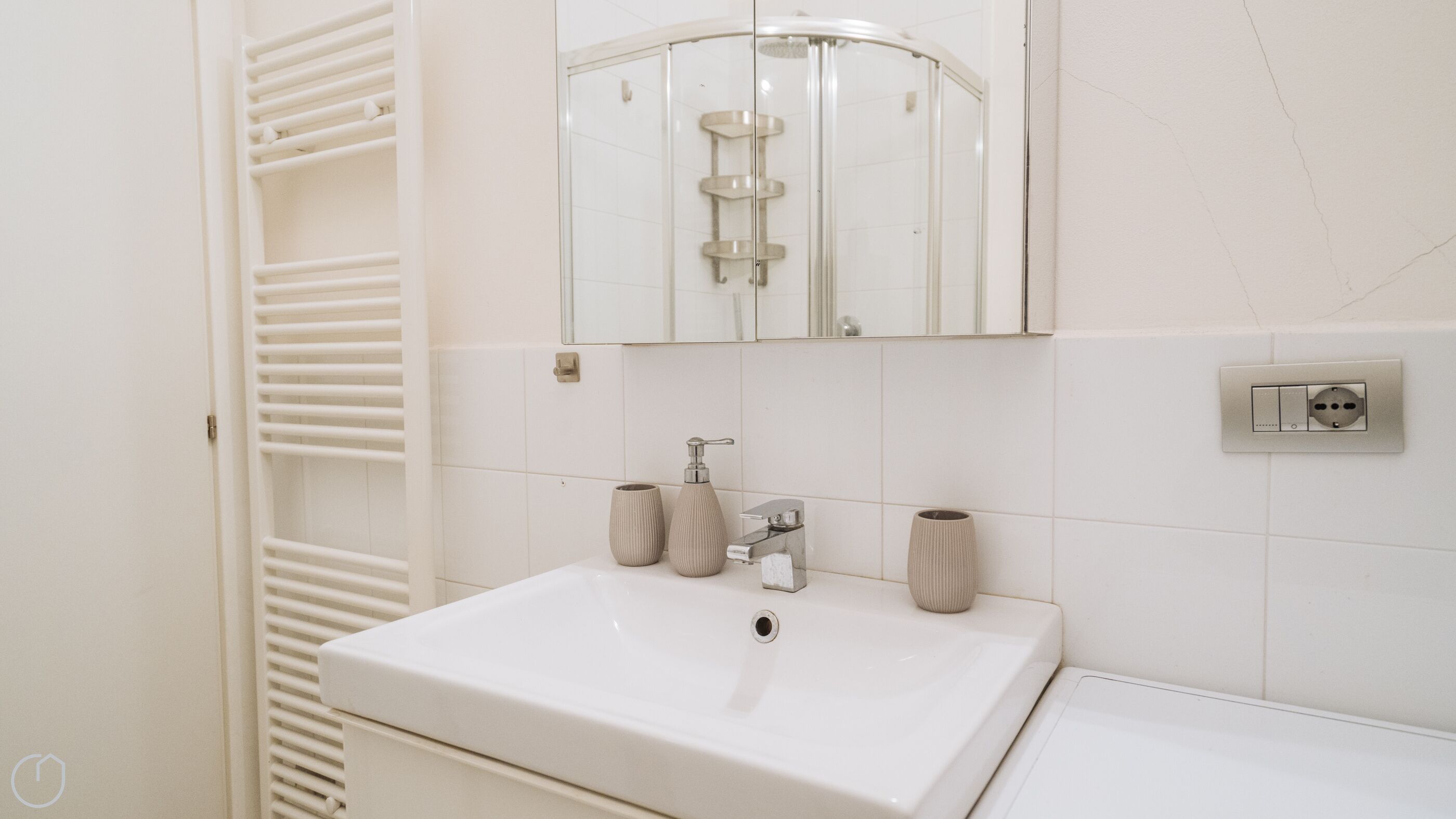A bathroom with a white sink, a mirror above it, and a shower enclosure.