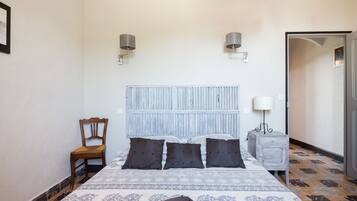 A bedroom with a bed, a chair, a nightstand, and a door.