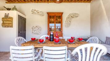 A wooden dining table with white chairs, a coffee maker, and red bowls.