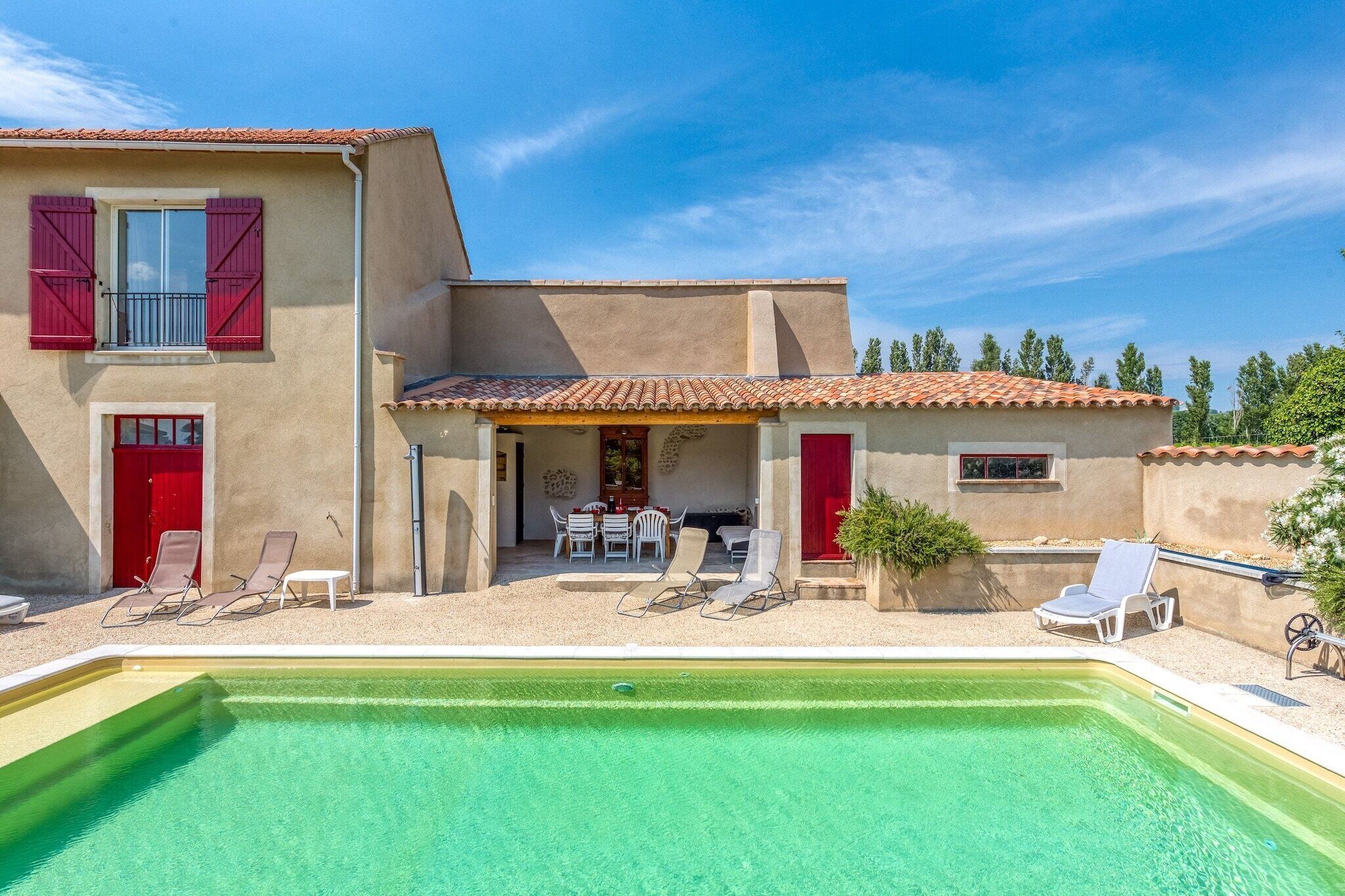 A two-story house with a swimming pool, outdoor seating, and a red door.