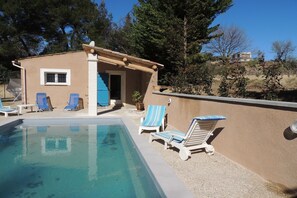 A pool area with lounge chairs and a small building with a window. - Holiday Home in Buisson with Private Pool (Buisson)